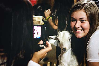 Two young women take photos with the animals at the petting zoo.