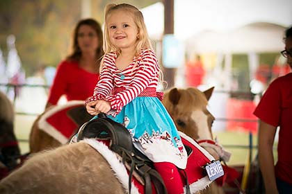A girl riding one of the ponies at the Sights & Sounds petting zoo.