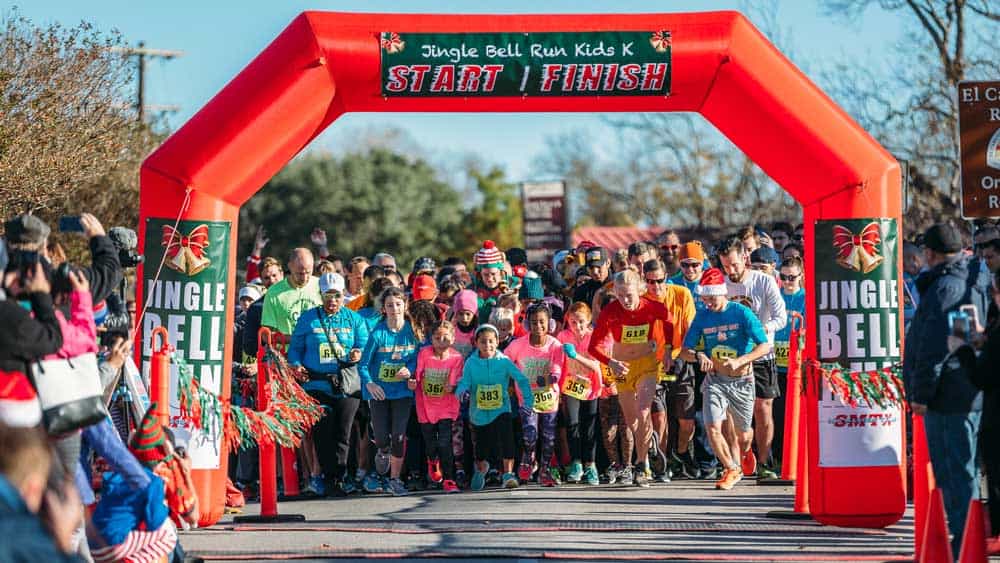 Runners crossing the finish line of the Jingle Bell Run 5k at the Sights & Sounds of Christmas festival in San Marcos
