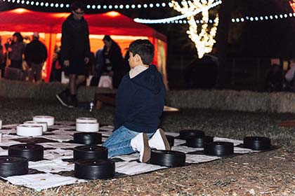 A boy sits on the giant Checkers board.