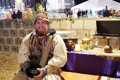 A volunteer dressed as a king poses with opulent gifts at the Town of Bethlehem.