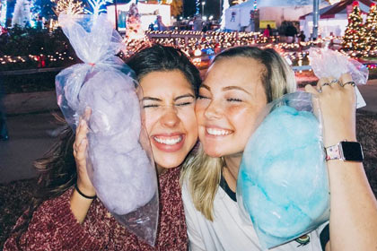 Two festival-goers pose with cotton candy purchased from a vendor at Santa's Gift Shop.